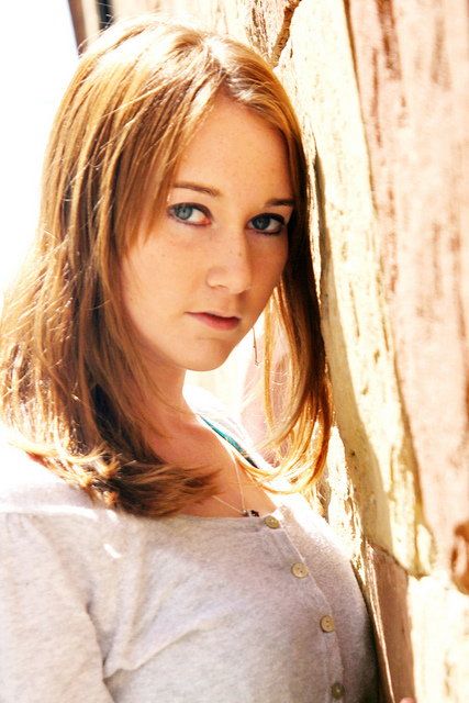 Soft-light portrait of a model leaning against a sunlit wall