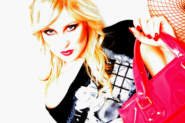 High-key studio shot of a blonde model with a pink handbag and fishnet detail