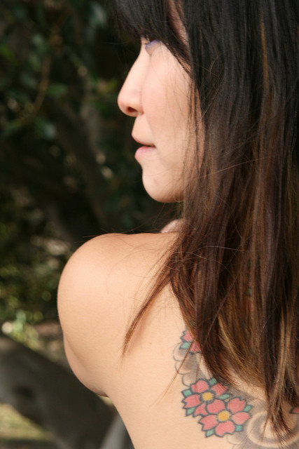 Portrait from behind of a dark-haired model with a tattooed shoulder